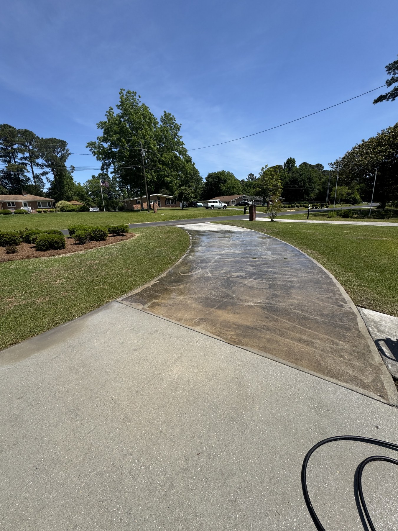 Driveway cleaning in progress showing clean concrete beside buildup